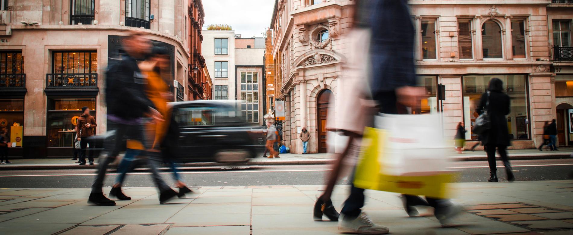 Shoppers walking past retail storefronts on a busy city high street