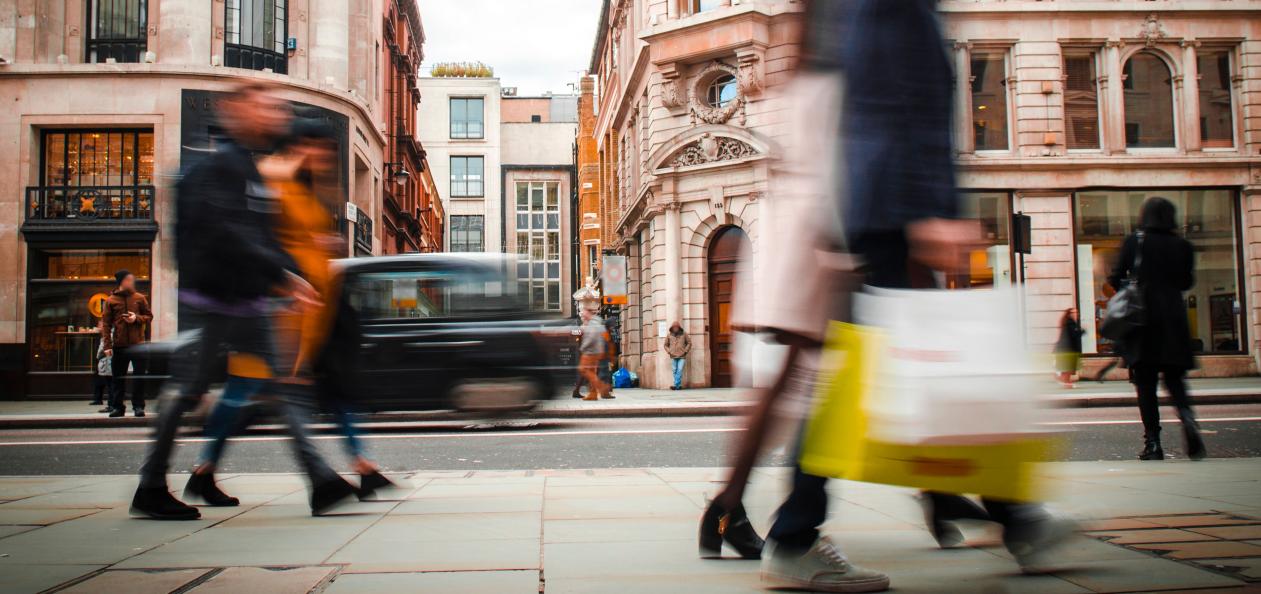 Shoppers walking past retail storefronts on a busy city high street
